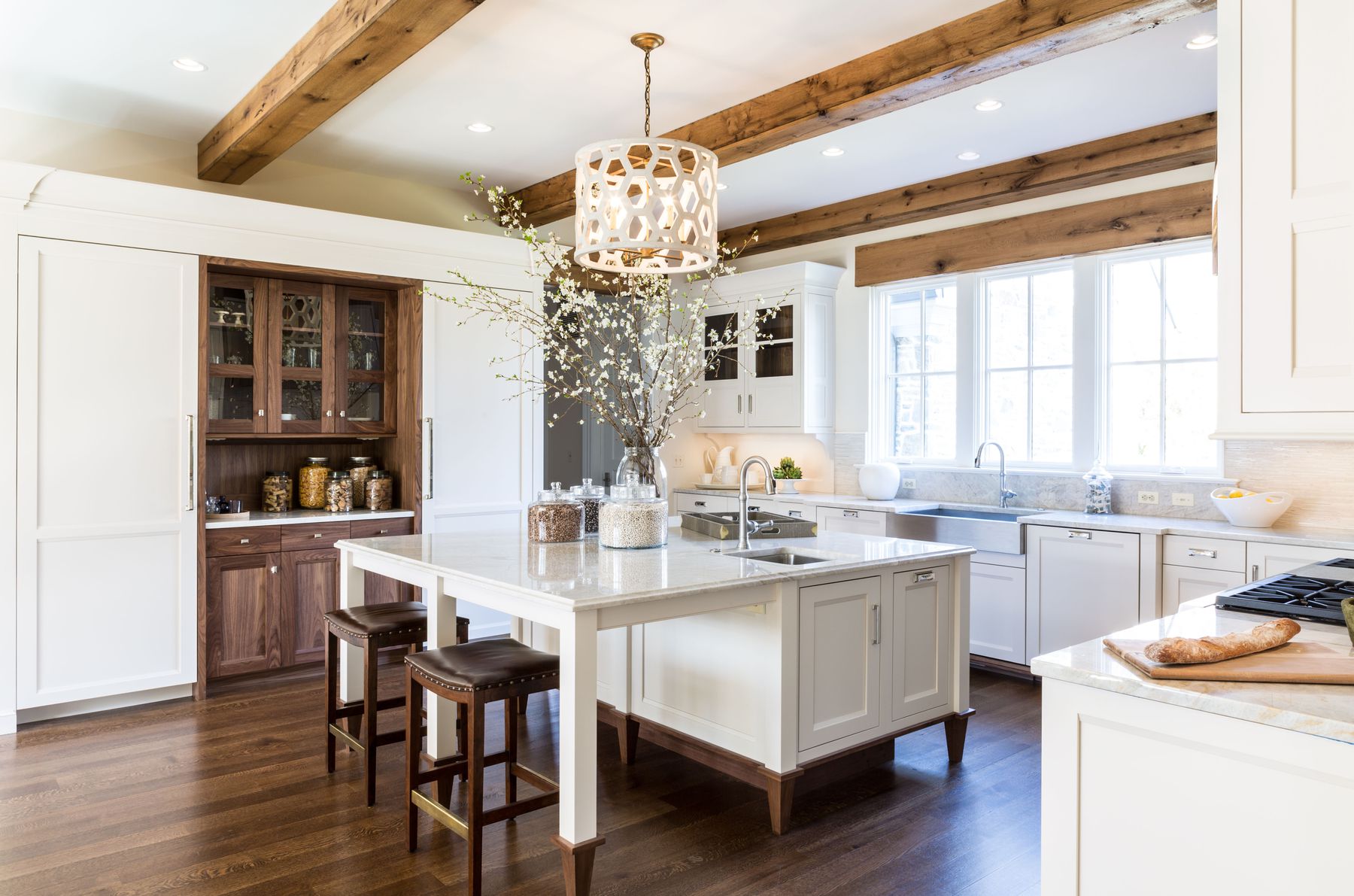 A kitchen with white cabinets and wooden floors.