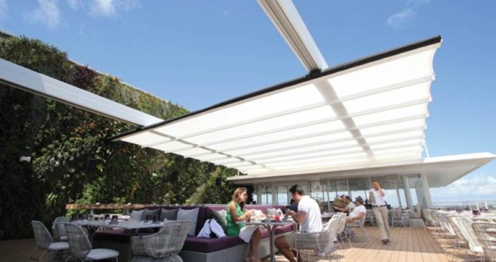 A group of people sitting under an awning.