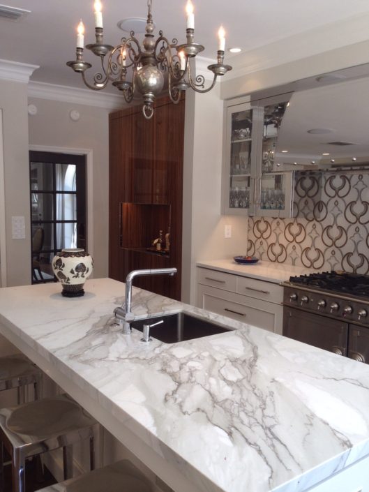 A kitchen with marble counter tops and a chandelier.