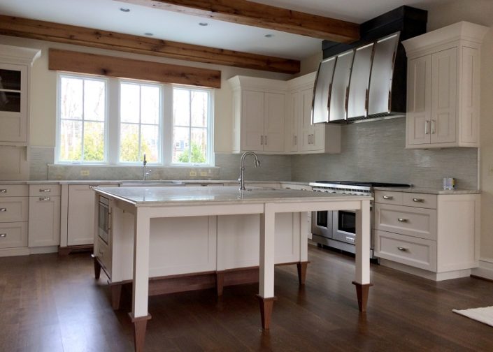 A kitchen with white cabinets and wood floors.