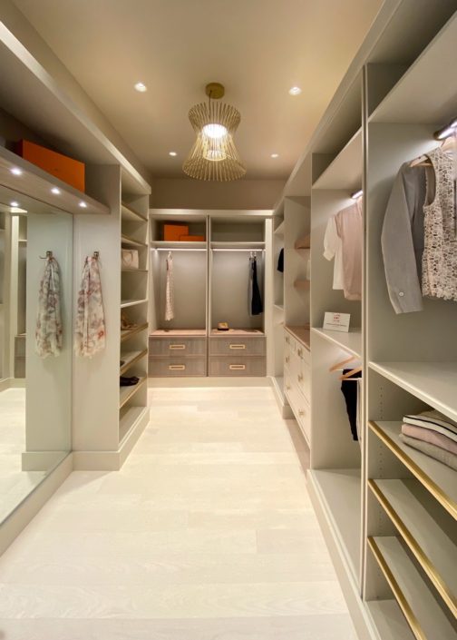 A walk in closet with many shelves and clothes.