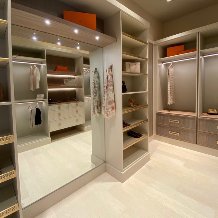 A large walk in closet with a mirror and shelves.