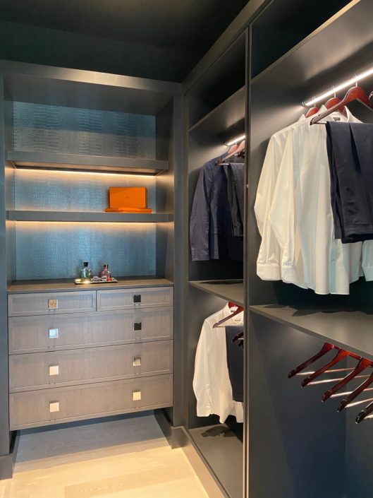 A walk in closet with clothes hanging on the rail.