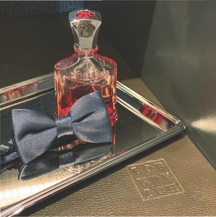 A bow tie and a bottle of alcohol on top of a tray.