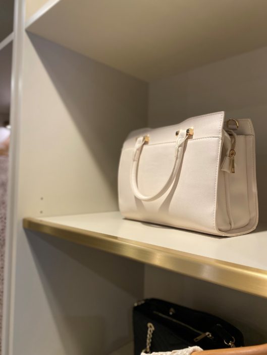 A white purse sitting on top of a shelf.