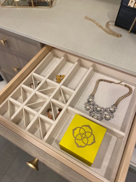 A drawer with many compartments and a necklace