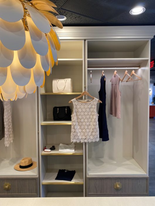 A white closet with clothes hanging on the wall.