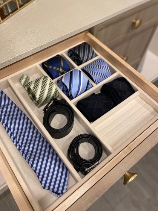 A drawer with ties and other accessories in it.